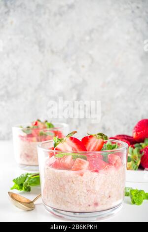 Set vari frutta durante la notte farinata d'avena. Porridge di avena con fragola, banane, cioccolato, noci in piccoli vasi porzione. Colazione estiva con farinata d'avena. Sano Foto Stock