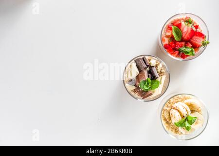 Set vari frutta durante la notte farinata d'avena. Porridge di avena con fragola, banane, cioccolato, noci in piccoli vasi porzione. Colazione estiva con farinata d'avena. Sano Foto Stock