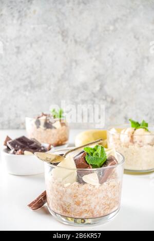 Set vari frutta durante la notte farinata d'avena. Porridge di avena con fragola, banane, cioccolato, noci in piccoli vasi porzione. Colazione estiva con farinata d'avena. Sano Foto Stock