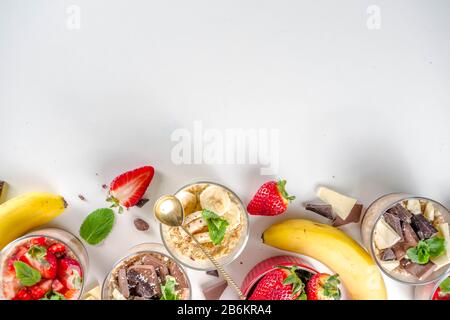 Set vari frutta durante la notte farinata d'avena. Porridge di avena con fragola, banane, cioccolato, noci in piccoli vasi porzione. Colazione estiva con farinata d'avena. Sano Foto Stock