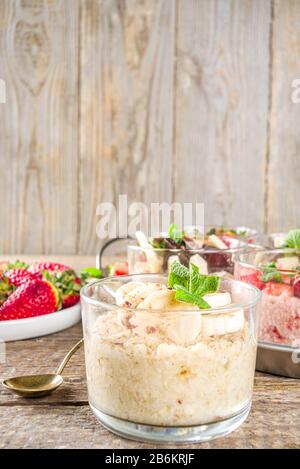 Set vari frutta durante la notte farinata d'avena. Porridge di avena con fragola, banane, cioccolato, noci in piccoli vasi porzione. Colazione estiva con farinata d'avena. Sano Foto Stock