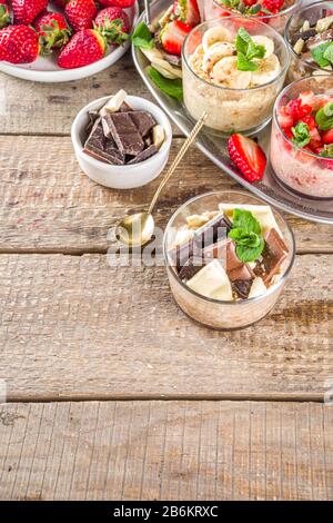 Set vari frutta durante la notte farinata d'avena. Porridge di avena con fragola, banane, cioccolato, noci in piccoli vasi porzione. Colazione estiva con farinata d'avena. Sano Foto Stock