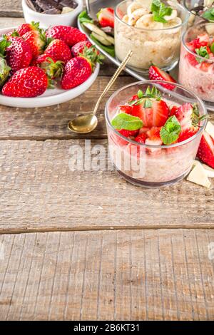 Set vari frutta durante la notte farinata d'avena. Porridge di avena con fragola, banane, cioccolato, noci in piccoli vasi porzione. Colazione estiva con farinata d'avena. Sano Foto Stock