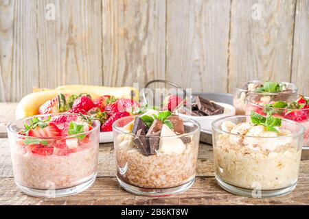 Set vari frutta durante la notte farinata d'avena. Porridge di avena con fragola, banane, cioccolato, noci in piccoli vasi porzione. Colazione estiva con farinata d'avena. Sano Foto Stock