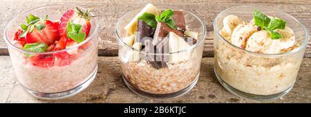 Set vari frutta durante la notte farinata d'avena. Porridge di avena con fragola, banane, cioccolato, noci in piccoli vasi porzione. Colazione estiva con farinata d'avena. Sano Foto Stock