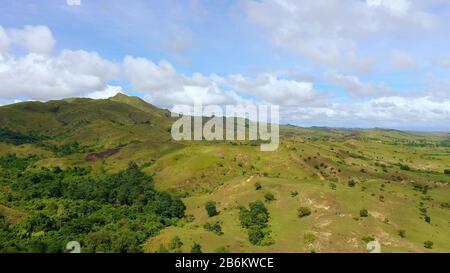 Verdi colline e cielo blu con nuvole. Bellissimo paesaggio sull'isola di Luzon, vista aerea. Paesaggio montano in condizioni di sole. Foto Stock