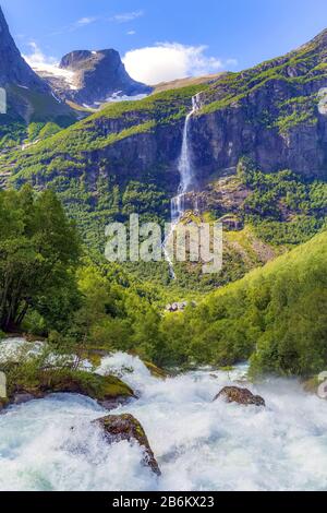 Paesaggio con fiume nei pressi di Briksdal o ghiacciaio Briksdalsbreen in Olden, Norvegia con il verde delle montagne, neve e cascata Foto Stock
