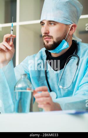 Il medico entra in una soluzione iniettabile in una siringa Foto Stock