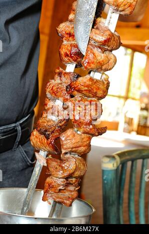 Cameriere mani taglio picanha, tradizionale barbecue brasiliano Foto Stock