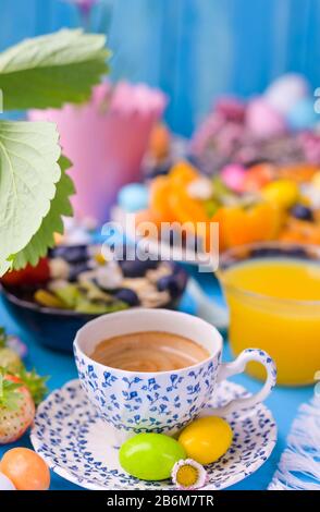 Colazione di Pasqua. Caffè espresso aromatico fresco, succo d'arancia, uova di pasqua, muesli, su sfondo blu. Spazio di copia Foto Stock