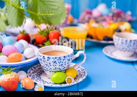 Colazione di Pasqua. Tazza d'epoca con caffè espresso, succo d'arancia, uova di pasqua, muesli, miele su sfondo blu di legno. Spazio di copia Foto Stock