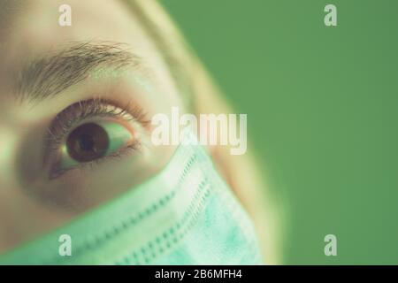 Parte di un volto femminile in una maschera medica. Primo piano Foto Stock