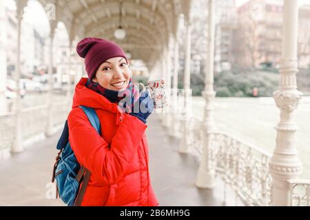 Happy woman beve acqua da una sorgente termale calda a Karlovy Vary, Repubblica Ceca in inverno Foto Stock