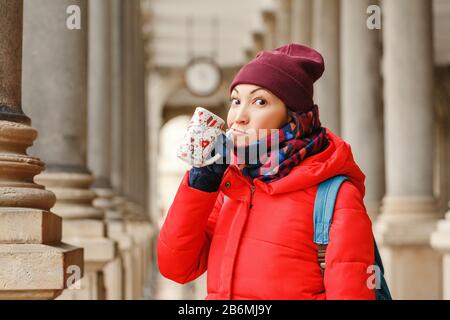 Happy woman beve acqua da una sorgente termale calda a Karlovy Vary, Repubblica Ceca in inverno Foto Stock