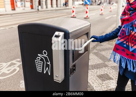 Donna che lancia rifiuti nel contenitore di riciclaggio della strada Foto Stock
