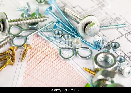 tecnologia e lavorazione dei metalli. Bullone e dado in metallo sullo sfondo dei disegni stampati Foto Stock