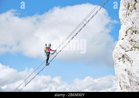 Scala al concetto di paradiso con un alpinista femminile che tiene il suo pugno in alto e stretto, sulla scala via ferrata a Intersport Klettersteig Donnerkogel percorso Foto Stock