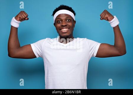 Felice uomo forte in palestra sportiva, mostra muscoli, felice di essere in forma e sano. Sportivo ama l'allenamento, ha corpo atletico Foto Stock