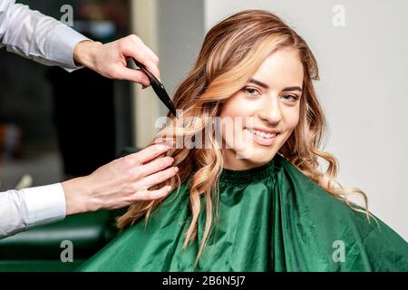 Il parrucchiere spazzola la ragazza. Felice giovane donna e parrucchiere con brash che fa acconciatura al salone dei capelli. Foto Stock