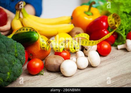 Verdure fresche e frutta a tavola intera con metro a nastro giallo Foto Stock