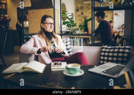 Sognando la signora graziosa che pensa alle idee seduta nel caffè, professione creativa. Tema moderno blogger femminile. Giovane donna con la penna in mano che pensa sopra Foto Stock