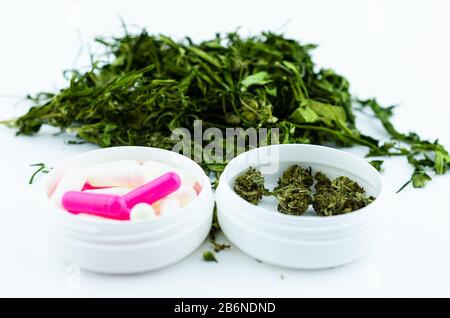 Una scatola medica bianca di cannabis e una scatola bianca di pillole colorate. Concetto di terapia medica a base di cannabis Foto Stock