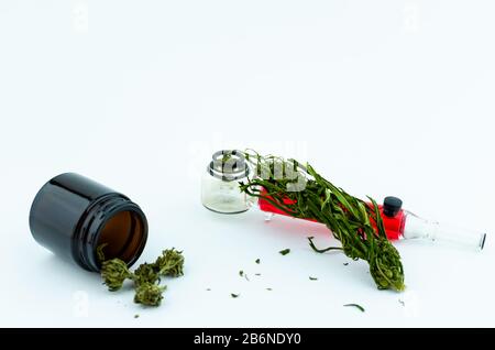 Flaconcino medico di vetro nero di boccioli di cannabis all'interno e tubo di fumo di vetro sullo sfondo. Concetto di cannabis medica Foto Stock