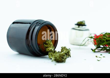 Flaconcino medico di vetro nero di boccioli di cannabis all'interno e tubo di fumo di vetro sullo sfondo. Concetto di cannabis medica Foto Stock