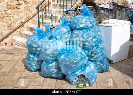 Immondizia in sacchetti di plastica blu sulla strada della città orientale. In sacchetti di plastica blu bottiglie Foto Stock