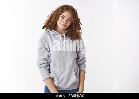 Allegra ragazza caucasica giovane rossa con sconsiderate acne che indossa casual cappuccio tilt testa sorridente amichevole fotocamera appeso intorno amici partito Foto Stock