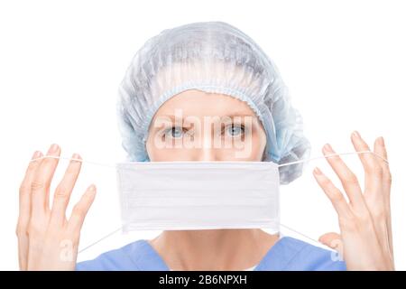 Ritratto di attraente giovane chirurgo con occhi blu che mette maschera del viso mentre si prepara per il funzionamento Foto Stock