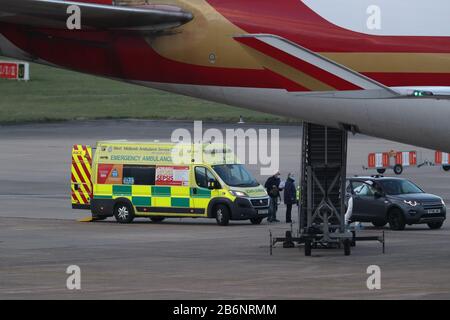 Un membro del NHS West Midlands Ambulance Service, indossando indumenti protettivi e una maschera facciale, parla ai passeggeri (a sinistra) dalla nave da crociera Grand Princess, colpita dal coronavirus, dopo che sono arrivati all'aeroporto di Birmingham dopo il loro rimpatrio nel Regno Unito dagli Stati Uniti. Foto PA. Data Immagine: Mercoledì 11 Marzo 2020. Circa 140 vacanzieri britannici erano stati bloccati sulla nave al largo della costa occidentale dell'America dopo che 21 persone hanno provato positivo per il virus a bordo. Vedi la storia PA SALUTE Coronavirru. Photo credit dovrebbe leggere: Steve Parsons/PA Wire Foto Stock