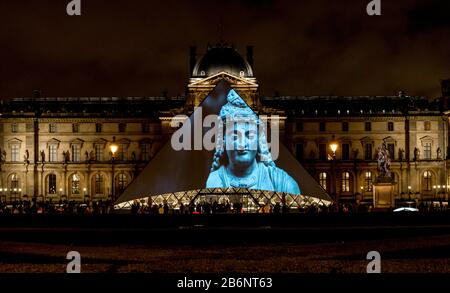 Mostre di collezione del Louvre esposte su un ingresso a piramide di vetro in serata, Parigi, Francia Foto Stock