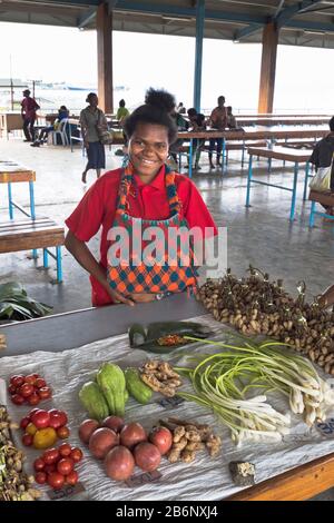 dh PNG mercato locale fornitore ALOTAU PAPUA NUOVA GUINEA sorridente donna nativa a frutta bancarella verdure persone gente del posto Foto Stock