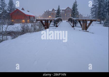 Nevoso inverno mattina vista di un ponte pedonale sopra Il Gendeman's Creek a Canmore, Alberta, Canada Foto Stock