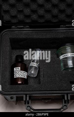 Soluzione igienizzante per uso medico a base di alcol liquido per la disinfezione delle apparecchiature per le mani, cassetta di emergenza con maschere facciali. Foto Stock