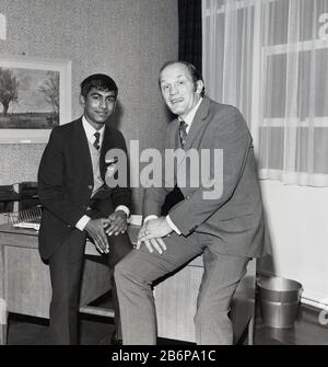 1972, storico, Leggendario pugile britannico di peso pesante Henry Cooper in posa per un'immagine con un allievo in una visita ad una scuola secondaria a Catford, Londra sud-orientale, Inghilterra. Uno sportivo popolare, Cooper, che era un londinese, nato a Lambeth, è stato il primo a vincere due volte il BBC Sports Personality of the Year Award. È anche l'unico pugile ad essere stato assegnato un knighthood. Foto Stock