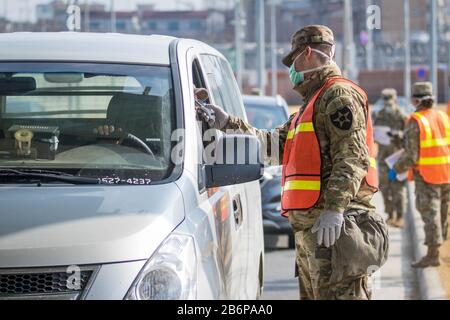 Soldato che prende la temperatura di un commuter per lo screening di COVID-19 presso la Garrison Humphreys (Camp Humphreys) dell'esercito degli Stati Uniti, Corea del Sud, 27 febbraio 2020. Foto Stock