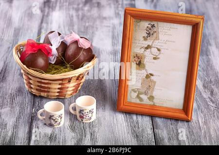 Cioccolato uova di pasqua in un cestino su un tavolo di legno grigio con decorazione. Concetto di Pasqua Foto Stock