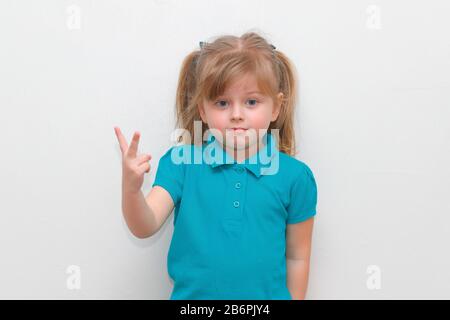 Una ragazza di 4 anni cheey che si attacca 2 dita in su. Foto Stock