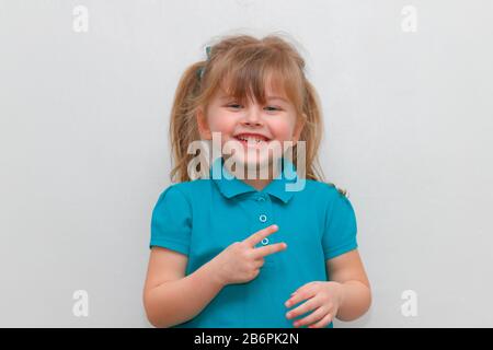 Una ragazza di 4 anni cheey che si attacca 2 dita in su. Foto Stock