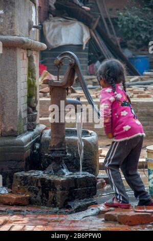 Bambina che ottiene l'acqua dalla pompa Foto Stock