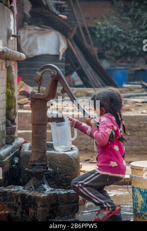 Bambina che ottiene l'acqua dalla pompa Foto Stock