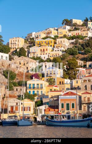 Costruzione facciate intorno porto in luce tardo pomeriggio Symi città Symi Isole Greche Grecia Foto Stock