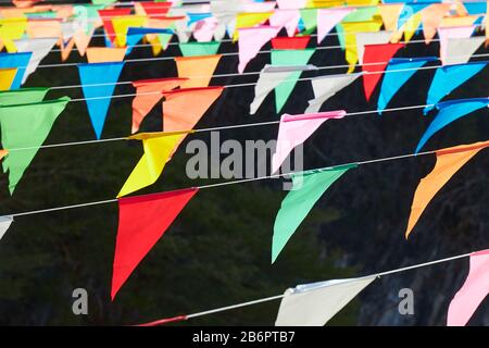 Molte bandiere triangolari multicolore appese sulle corde come decorazione di festa. Foto Stock