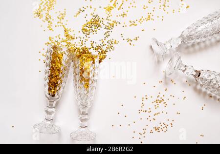 Schizzi di stelle d'oro da un vetro figurativo di vetro su un delicato sfondo beige. Layout pronto per le congratulazioni Foto Stock