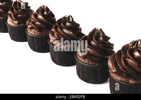 Deliziosi cupcake al cioccolato con sparkles d'oro cosparsi di glassa al cioccolato fiancheggiata diagonaly su sfondo bianco isolato. Mockup per il tuo design. Foto Stock