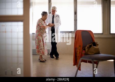 Una donna anziana viene aiutata da un medico. Foto Stock