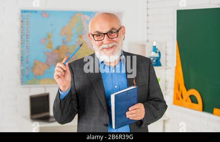 Docente esperto. Insegnante maturo godere di insegnamento. Condivisione delle conoscenze. Ottenere certificazioni per programmi specifici. Insegnante di uomo intelligente senior alla lavagna. Insegnante di vecchia generazione di scuola. Foto Stock