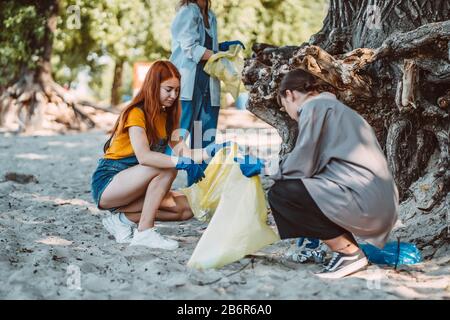 Amici che raccolgono rifiuti dal parco. Essi raccolgono la lettiera in sacco di spazzatura Foto Stock